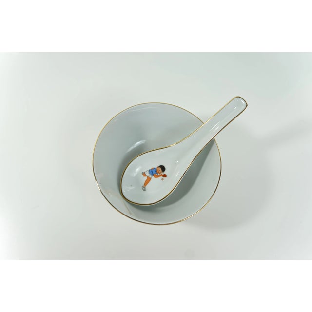 A set of matching porcelain bowl and spoon, featuring a ping pong or table tennis players motif. Crafted in Liling, China....