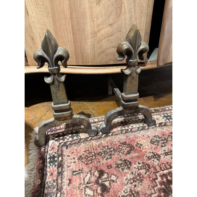 Pair of French Art Deco, Neoclassical brass fleur de lis andirons. Purchased in France. 9”l x 17”d x 14”h 47-070