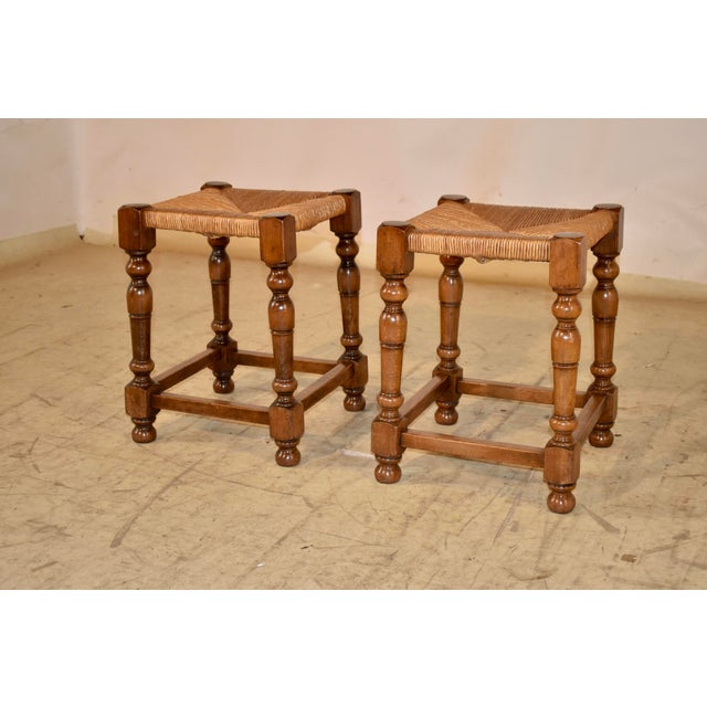 Late 19th century pair of French walnut stools with rush seats. The seats are hand-woven from rush, and are supported on...
