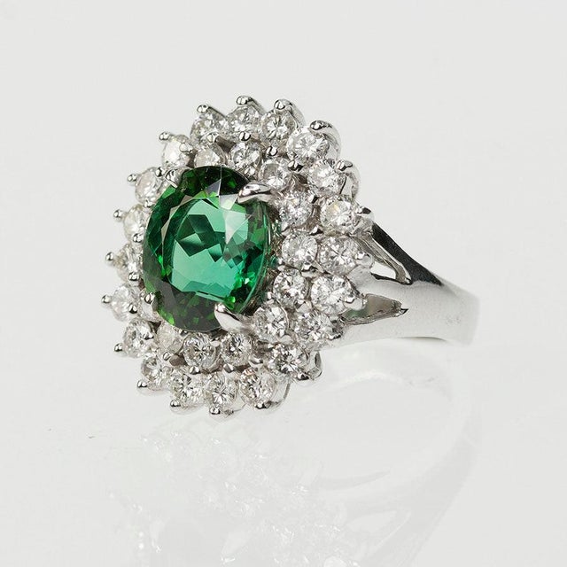 14k White gold ring set with 1 oval green tourmaline weighing 4.30 carats and 34 round diamonds weighing approximately...