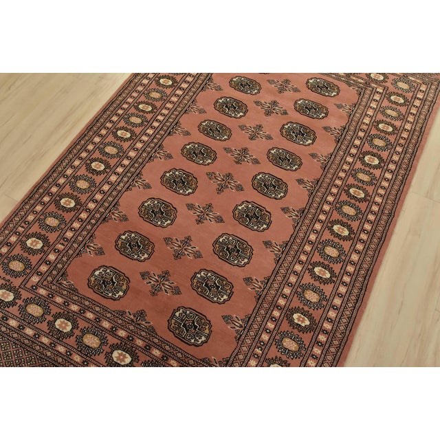 A tribal Bokhara rug hand-knotted with fine wool on a cotton foundation. This rug features rows of repeating medallions...