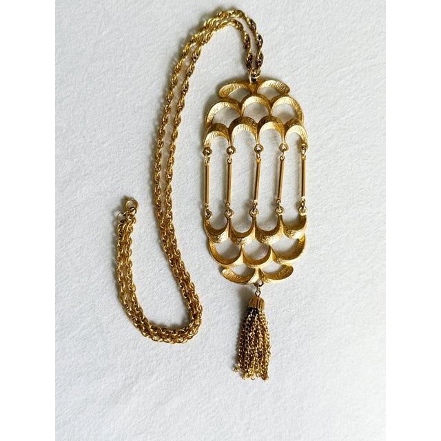 Sculptural 1970s statement necklace featuring an elongated, articulated birdcage pendant with tiered rows of curved...