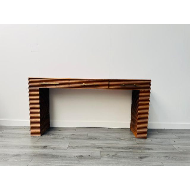 An Italian three drawers with brass handles console table with amazing lateral design carved into a solid oak wood frame ....