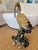 A clay sculpture of a spoonbill. It has many fine details and shows high craftsmanship. The Bird is resting on a bamboo...