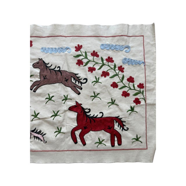 Hand-embroidered Suzani panel from Uzbekistan, worked in fine floss on a cream cotton ground. Six horses move across the...