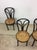 This set of four antique cafe chairs features bentwood construction, original finish, newer caned seats, and tall tapered...