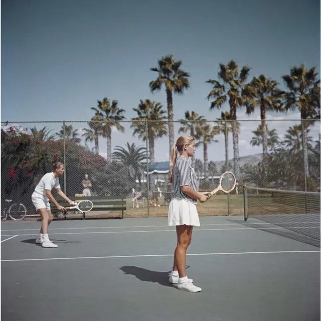 Tennis in San Diego 1956 A man and a woman playing tennis on a court surrounded by palm trees, San Diego, California,...
