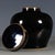 A sleek, glossy black glazed covered jar with a softly rounded belly and domed lid. The deep, mirror-like black glaze is...