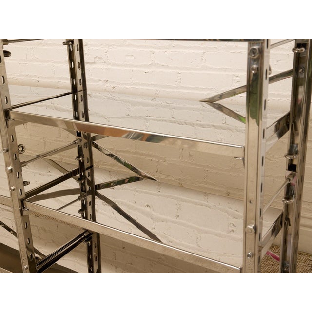 sleek architectural étagère console featuring a polished chrome frame, mirrored shelving, and graphic X-brace detailing...