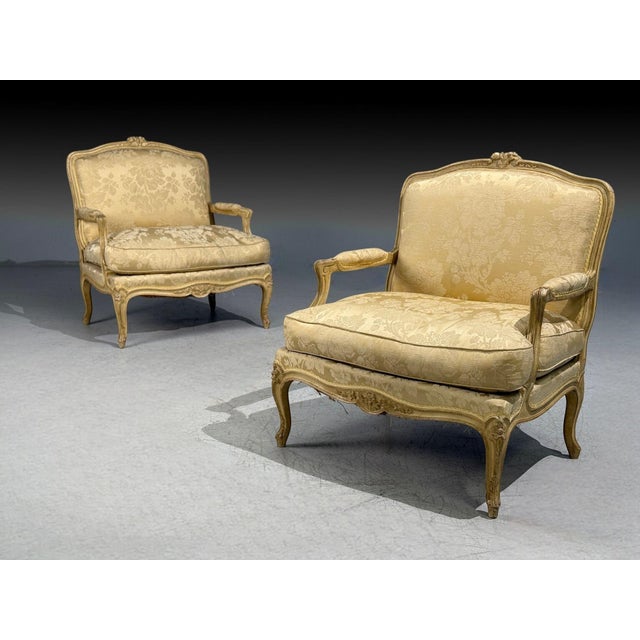 A pair of Louis XV style lounge chairs by Maison Jansen in their original fabric. A finely carved pair of chairs having a...