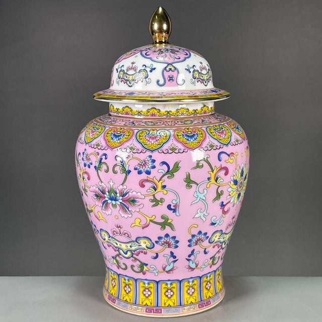 A vibrant Chinese porcelain covered jar featuring a bright pink ground. The jar is elaborately decorated with colorful...