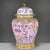 A vibrant Chinese porcelain covered jar featuring a bright pink ground. The jar is elaborately decorated with colorful...