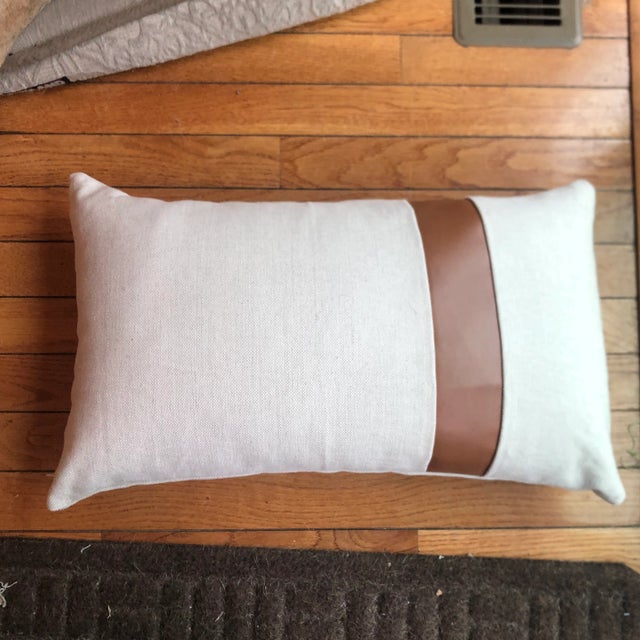 Chic pillow with leather strap in front solid fabric in back Poly insert fill Invisible zipper on side