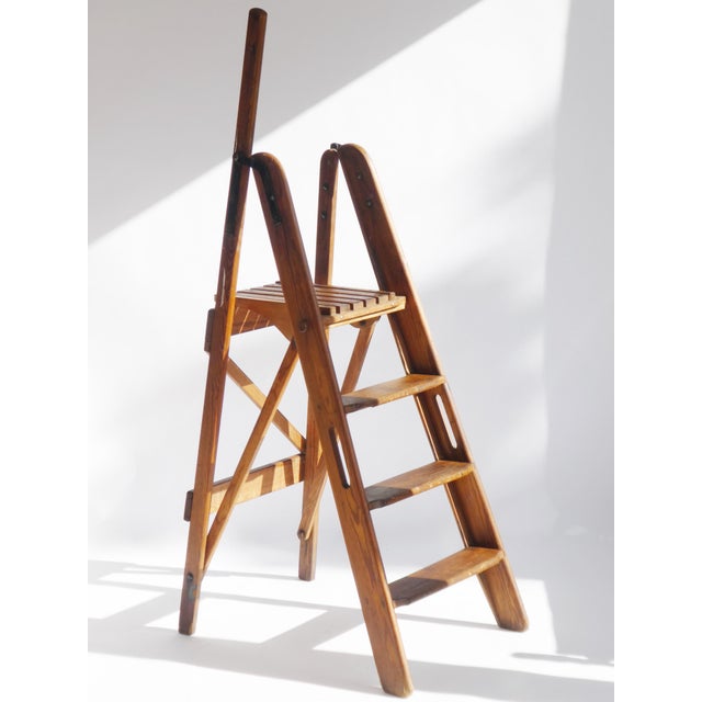 An antique painter's ladder made out of wood. The staircase is foldable and made in the Netherlands with its brand in the...