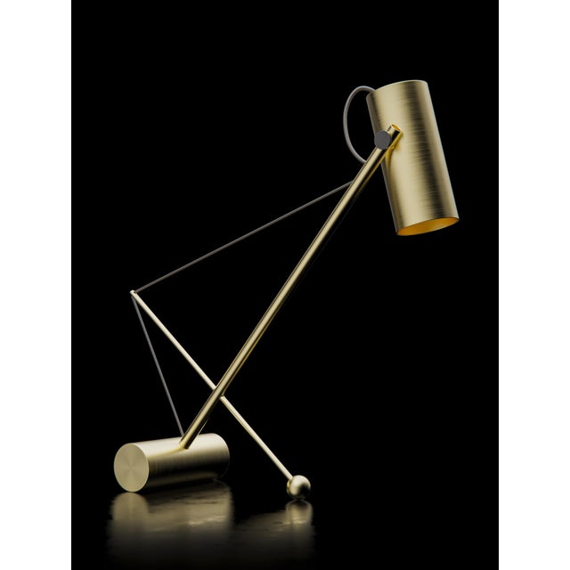 Reconfigurable table lamp with brushed brass structure. Thanks to the elastic band the lamp can be titled at will....