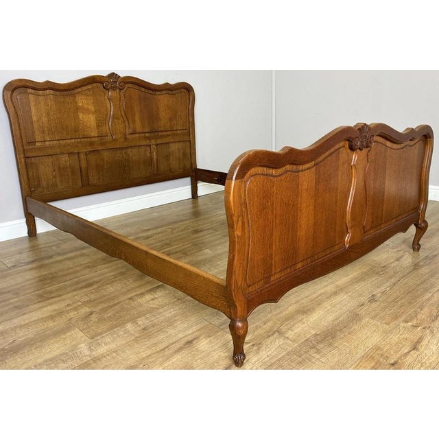 An elegant Vintage French Louis double bed in oak, featuring beautifully shaped head and footboards, decorative panelled...