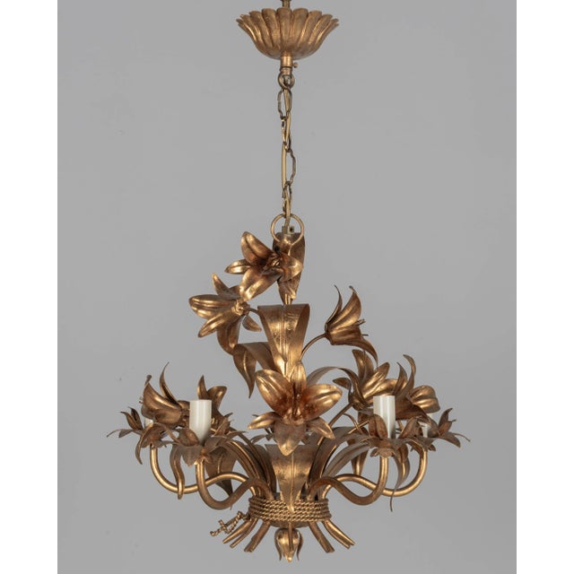 A Hollywood Regency style five-light gilt metal chandelier with tôle lily flowers. Original canopy and chain. Designed by...