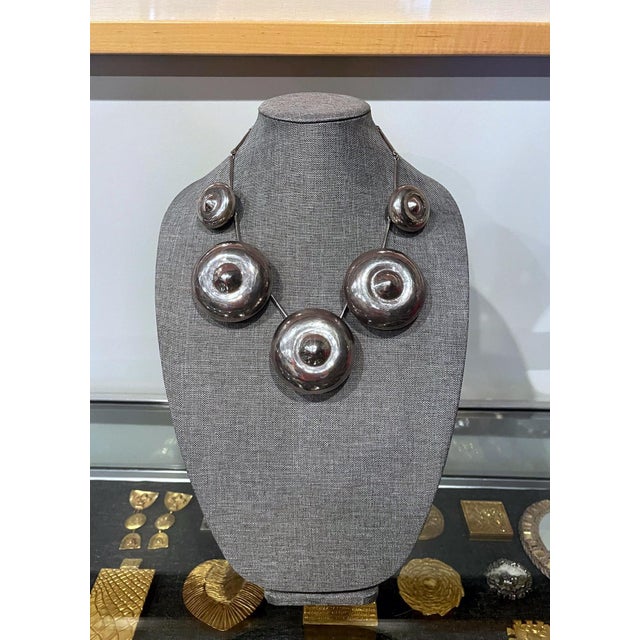 A bespoken sterling silver necklace with five roundel bell shape of gradual sizes linked by joint chains, designed and...
