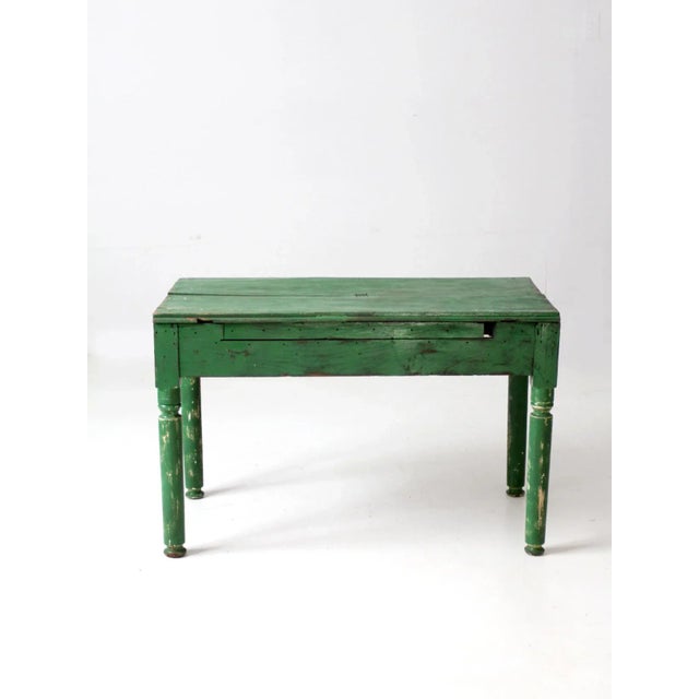 This is an antique wooden end table. Painted a rich verdant green the side table features turned legs and a two plank top....
