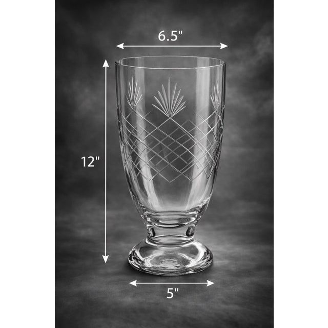 An elegant vintage pedestal vase featuring intricately etched glass with a refined starburst and lattice motif. The tall,...