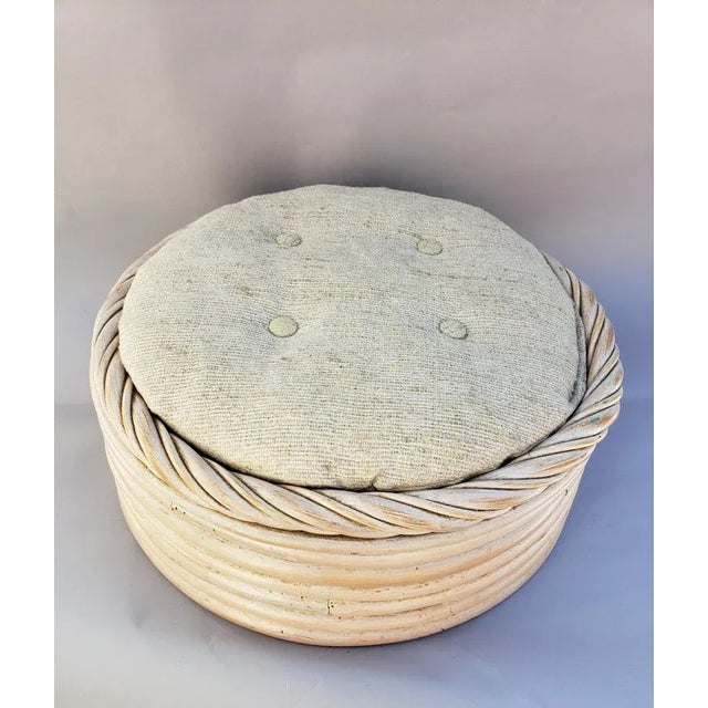 This vintage round footstool is crafted from hand-wrapped rattan finished in a soft whitewashed tone, topped with a...
