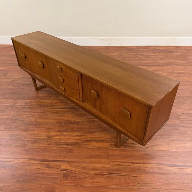 Vintage mid-century long teak sideboard with sled legs, made in the U.K. by Stonehill Furniture circa early 1970's. This...