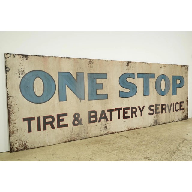 Reclaimed movie set sign made of aluminum in brown, tan, blue, red, and black colors. The sign reads "One Stop, Tire &...