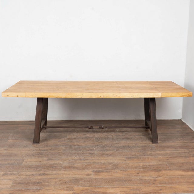 Reclaimed bowling lane wood tabletop sits upon a heavy iron base, creating a durable, industrial style dining or...