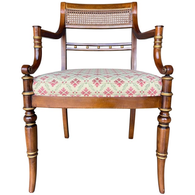 A refined Hickory Chair neoclassical armchair featuring a caned back, gilt accent detailing, and a sculptural wood frame....