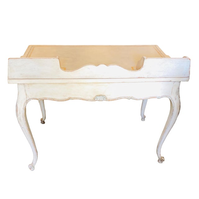 A decorative vintage Louis XV Style desk with a creamy white painted surface with light blue highlights. The flat top has...