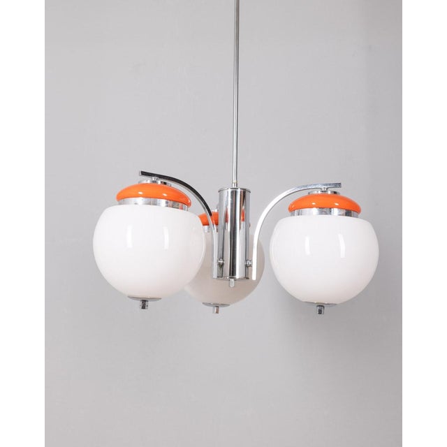 Chandelier with chromed and orange metal structure, with three white glass lampshades, Italian design, 1970s. Up to 250V...