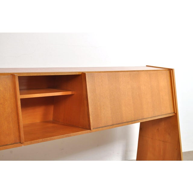 What a striking piece! this is, of course, due to the legs that angle forward and the entirely slanted front. The oak unit...