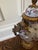 Porcelain covered urn with ornate bronze handles, base and trim. Features a crackled glaze finish with hand-painted pink...