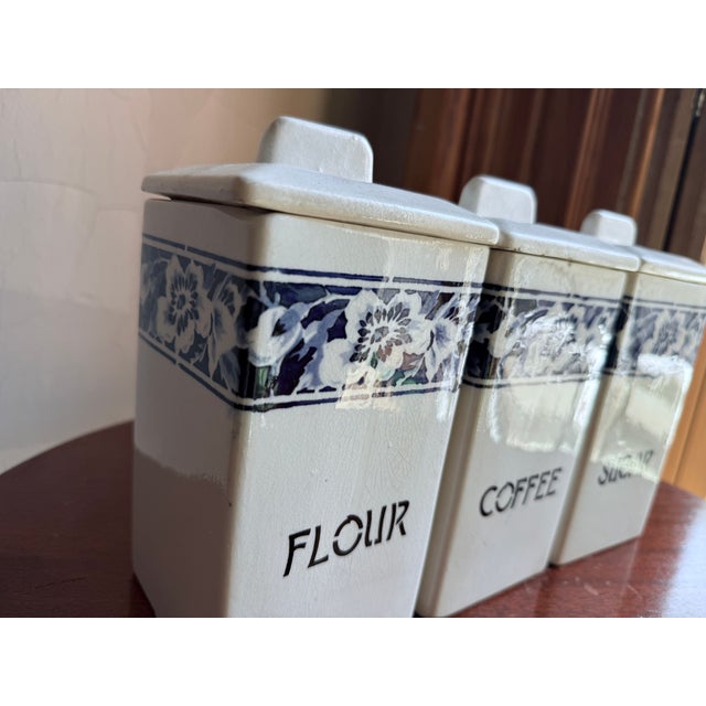 Mid-20th century German porcelain kitchen canister set in the Lilly pattern. White glazed bodies with a blue floral band...