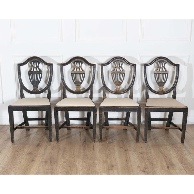 A superb suite of four 19th century Swedish chairs, each with a finely carved frame and escutcheon-shaped back centered by...