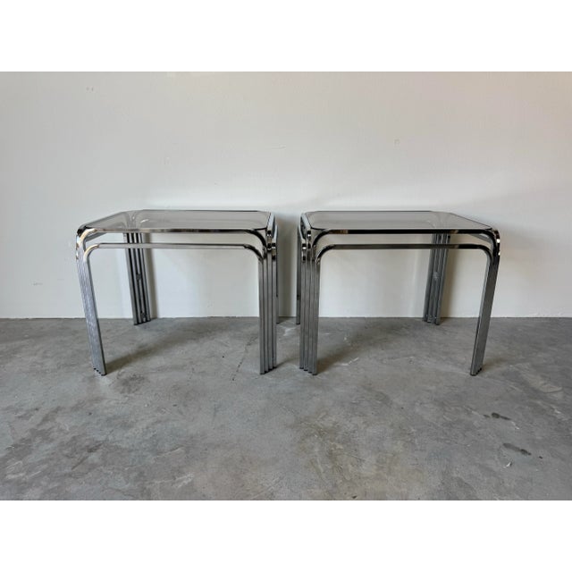 Elegant and timeless, this pair of mid-century modern side tables features sleek tubular chrome frames with rounded...