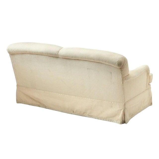 This classic two-seat sofa features soft cream-colored corduroy upholstery with a tailored skirt and plush removable...