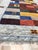 A 6' x 9' hand-knotted wool rug with a Gabbeh-style patchwork of red, blue, gold and brown blocks with small animal motifs...