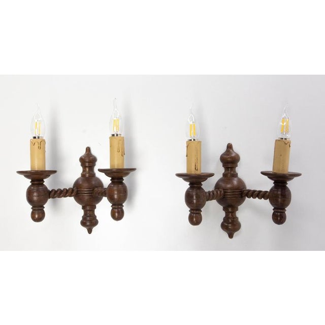 A pair of turned wood wall sconces with a rustic, handcrafted charm, inspired by the Neo-Regionalist style and French...