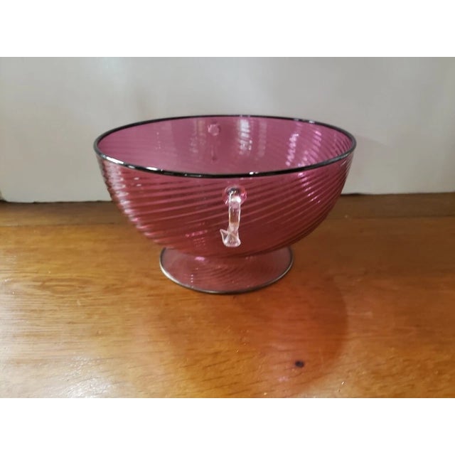 This is a Circa 1960 Italian MCM Murano Cranberry Glass Optic Swirl Pattern Footed Centerpiece Bowl with Applied...