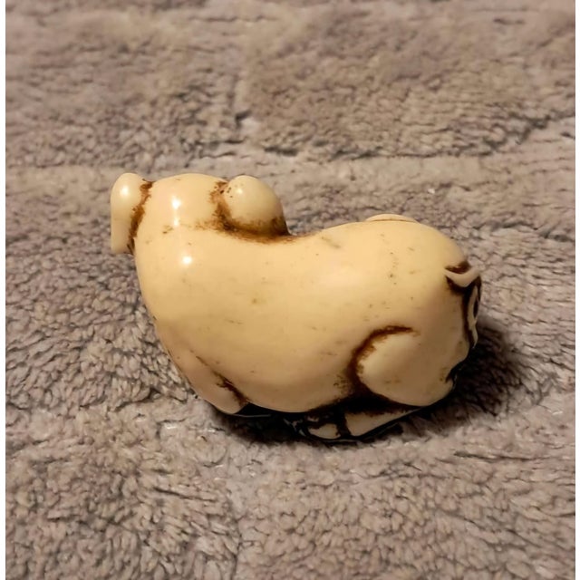 An exceptional and charming antique Chinese carved ivory netsuke depicting a recumbent pig. Expertly hand-carved from...