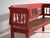 This antique red painted bench in pine wood is a bench with a backrest of turned spindles and armrests, with a continuous...