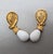 1980s goldtone tear drop white cabochon rhinestone top with textured goldtone loop surround with white resin drop with...