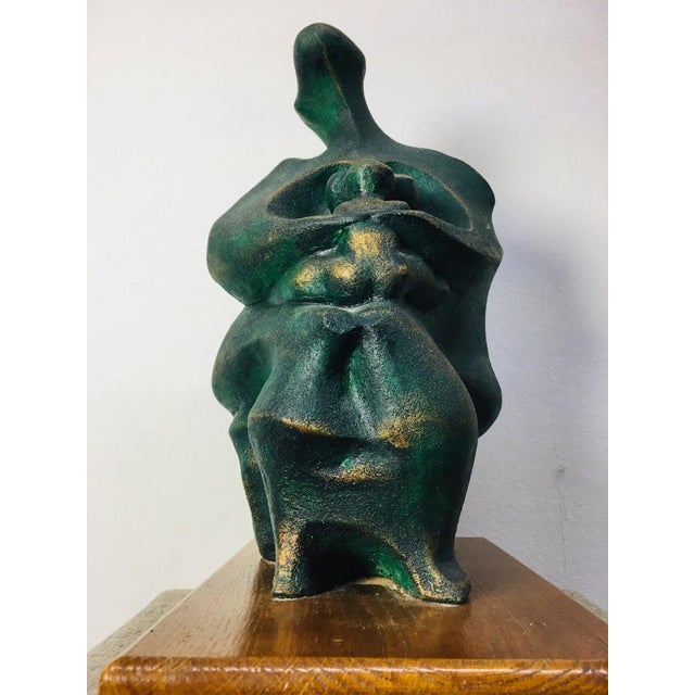 Abstract bronze-look ceramic sculpture portrays a mother hugging her child, art work of an unknown artist, unmarked.