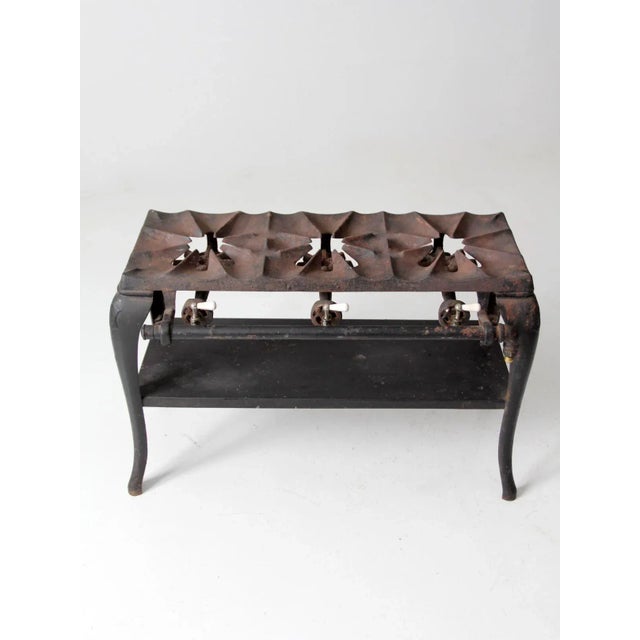 This antique cast iron stove features a sturdy three-burner design with classic industrial form and substantial weight....