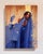 This artwork depicts a figure draped in a flowing blue garment, surrounded by a warm, abstract background that creates a...