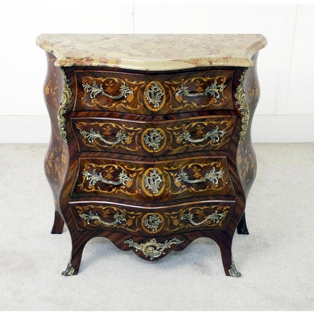 A striking french louis xv style bombe commode, richly decorated with marquetry inlays and ornate gilt metal mounts. Circa...