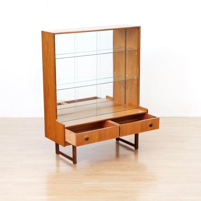 This vintage mid-century china cabinet was produced in England by Turnidge of London during the 1970s. This display...