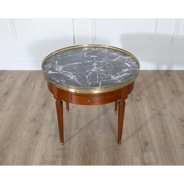 A refined French Louis XVI-style bouillotte coffee table, early 20th century, crafted in rich mahogany with elegant...