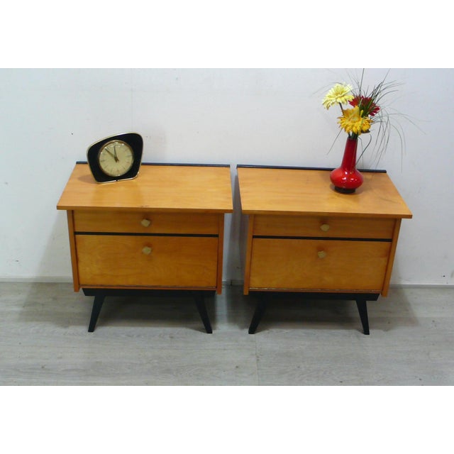 1960s set of two bedside tables, each with one drawer and a drop-down door, in ash veneer with black accents, from the...